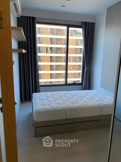 Modern bedroom with large window and minimalist design in urban apartment.