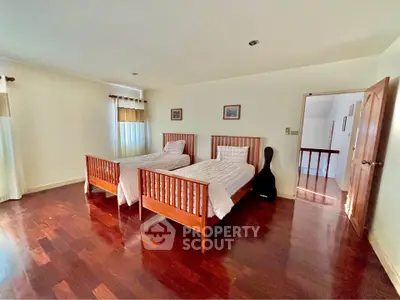 Spacious bedroom with twin beds and hardwood flooring in a cozy home.