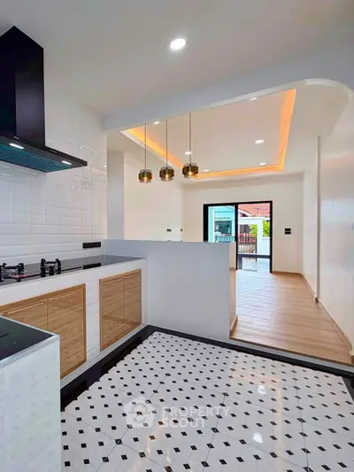 Modern kitchen with open layout and stylish lighting, featuring a gas stove and elegant tile flooring.
