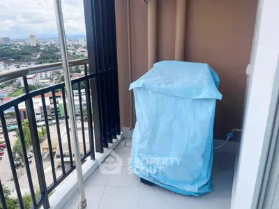 High-rise balcony with city view and covered appliance, ideal for urban living.