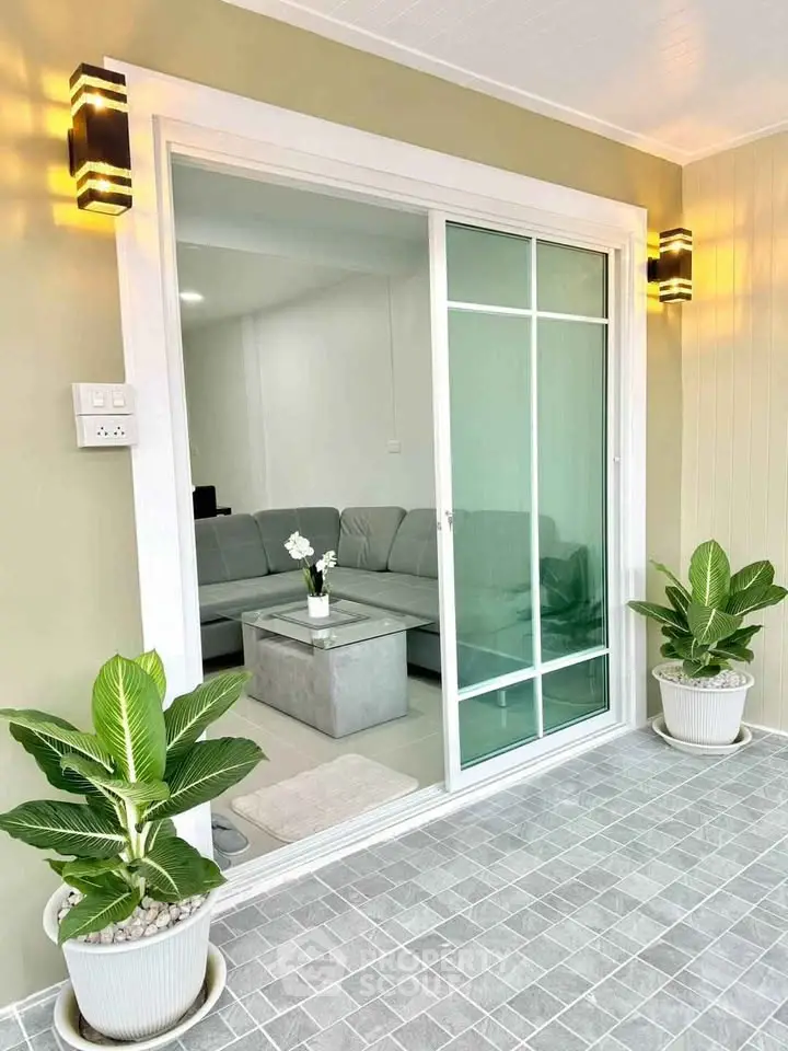 Modern living room with sliding glass doors and stylish lighting, featuring cozy seating and decorative plants.