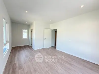 Spacious empty room with wooden flooring and white walls, ideal for customization.