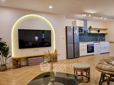 Modern living room with stylish kitchen, featuring large TV and elegant decor.