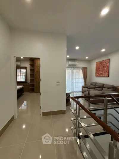 Modern living room with stylish decor and natural light, featuring a cozy sofa and elegant railing.