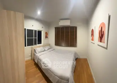 Cozy bedroom with wooden flooring and modern decor in a stylish apartment.