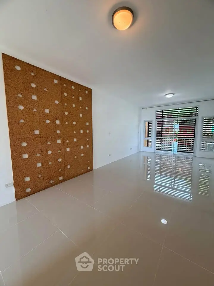Spacious modern living room with unique decorative wall and large windows for natural light.