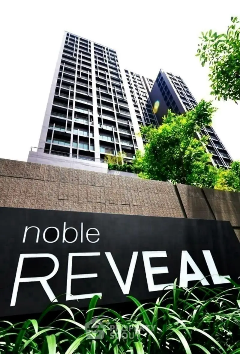 Modern high-rise building with lush greenery and bold signage, showcasing urban living at its finest.