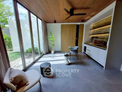 Modern living room with large windows, stylish ceiling, and elegant furniture, offering a serene garden view.