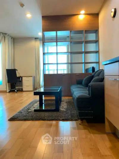 Modern living room with wooden flooring, stylish sofa, and built-in shelving unit.