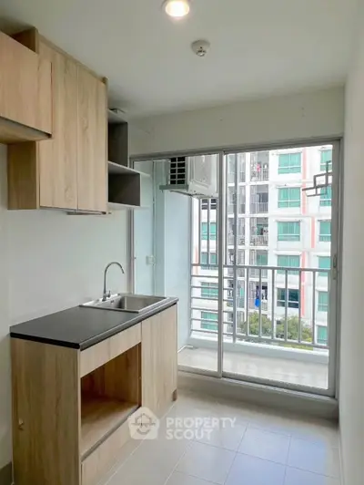 Modern kitchen with wooden cabinets and balcony view in a high-rise apartment.