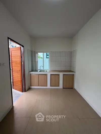 Minimalist kitchen with wooden cabinets and tiled backsplash, featuring an open layout and natural light.