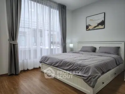 Modern bedroom with large window and stylish decor in a contemporary apartment.