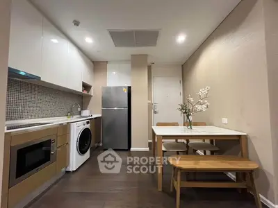 Modern kitchen with dining area, featuring sleek appliances and stylish decor.