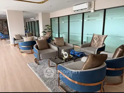Luxurious modern living room with elegant blue and gold armchairs, plush cushions, and sleek glass partitions.