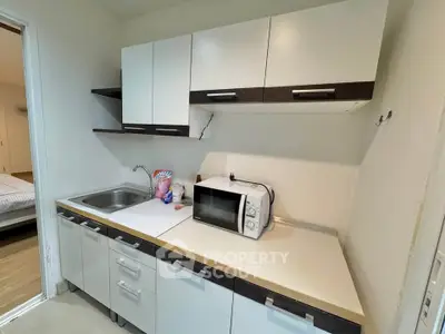 Compact kitchen with modern cabinets and microwave in cozy apartment