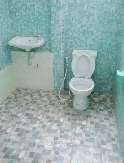 Simple bathroom with tiled walls and floor, featuring a toilet and sink.