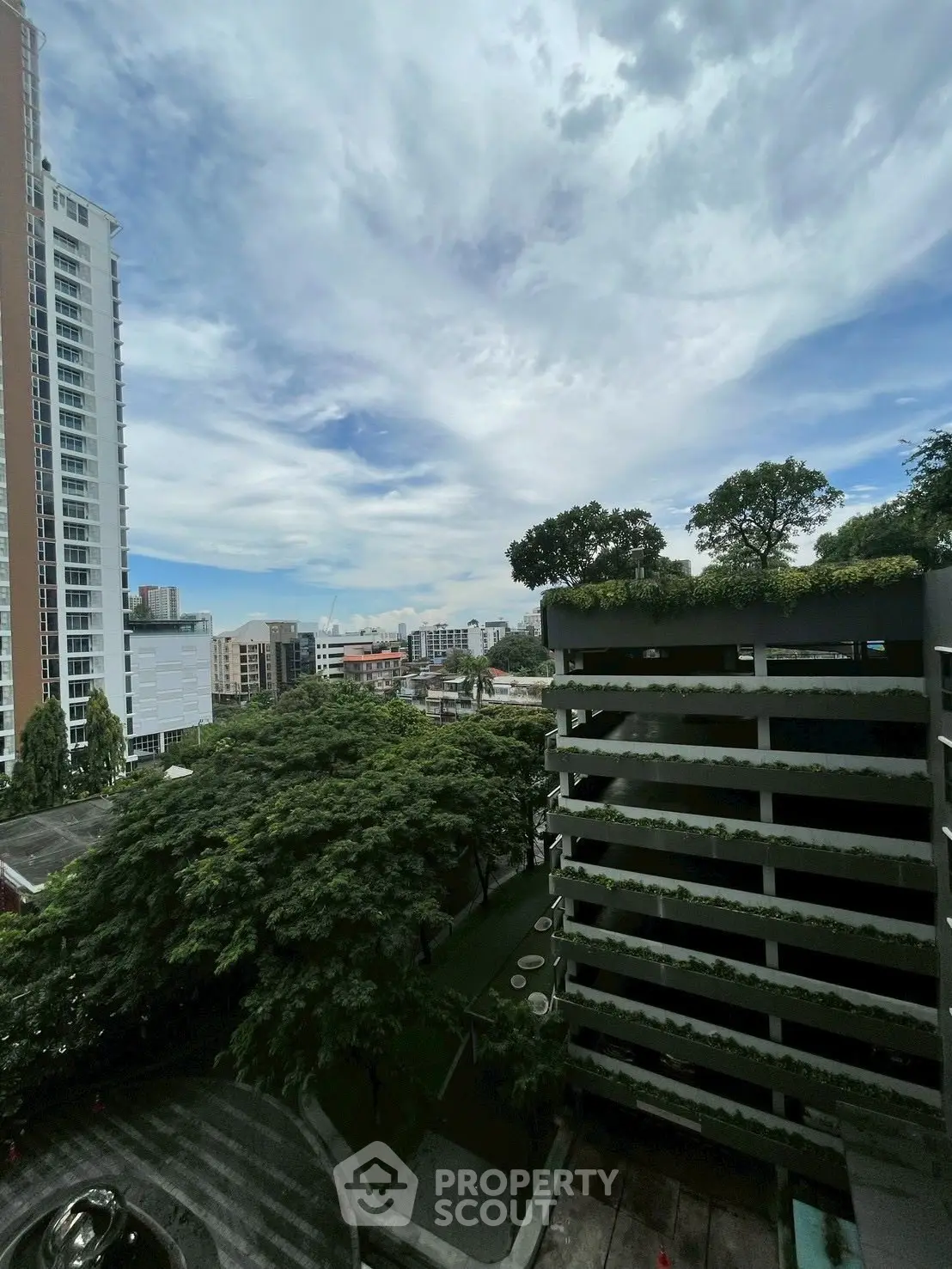 Stunning cityscape view from a high-rise building with lush greenery and modern architecture.
