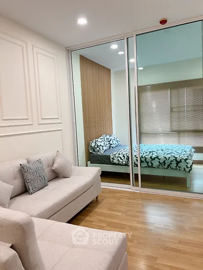 Modern apartment with stylish living room and cozy bedroom separated by glass wall.