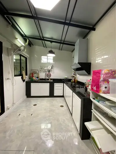 Spacious modern kitchen with sleek black countertops and white cabinetry, perfect for culinary enthusiasts.