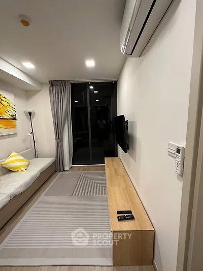 Modern living room with sleek design, featuring a wall-mounted TV, air conditioning, and stylish decor.