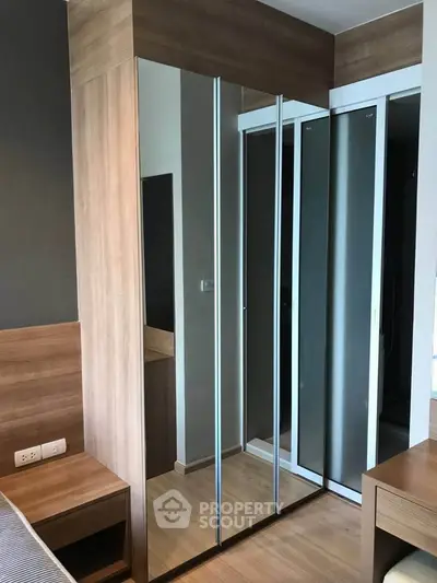 Modern bedroom with sleek mirrored wardrobe and wooden accents