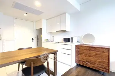 Modern kitchen with sleek cabinetry and dining area in bright apartment.