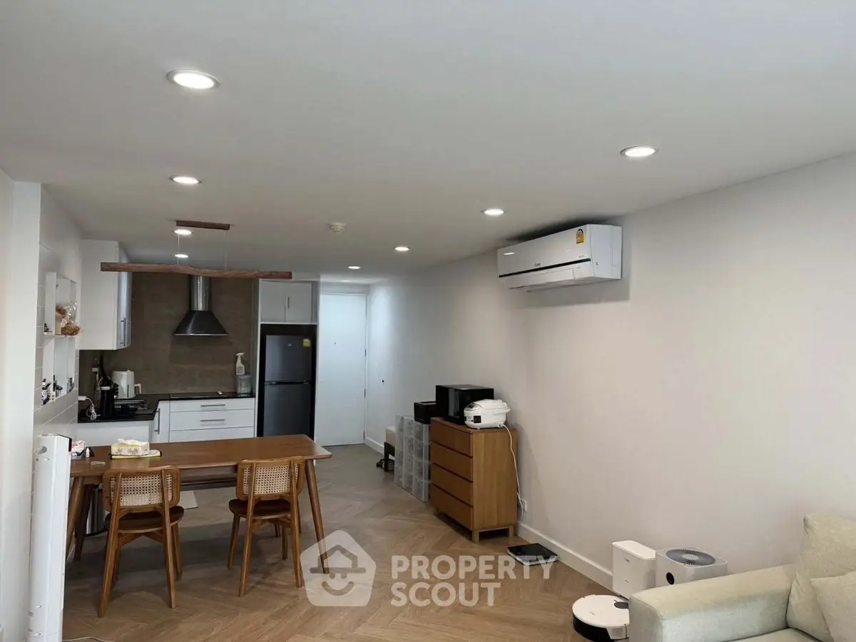 Modern open-plan living room with kitchen, featuring sleek appliances and stylish wooden flooring.