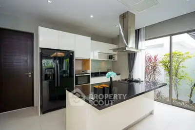 Modern kitchen with sleek black countertops and stainless steel appliances in a bright, open layout.