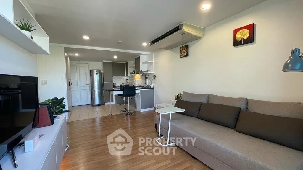 Modern living room with open kitchen, stylish decor, and cozy seating area.