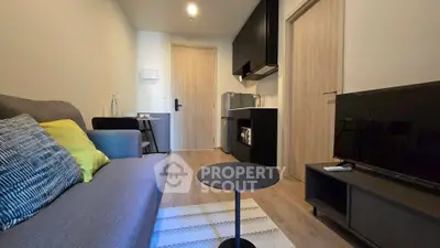 Modern living room with sleek furniture and compact kitchen area in a cozy apartment.