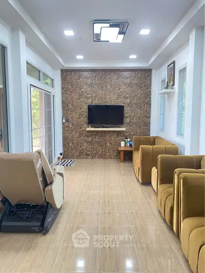 Spacious living room with modern seating and wall-mounted TV, featuring elegant tile flooring and ample natural light.