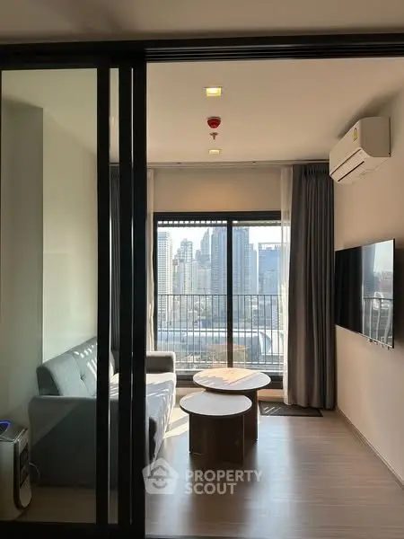 Modern living room with city view, featuring sleek furniture and large windows for natural light.