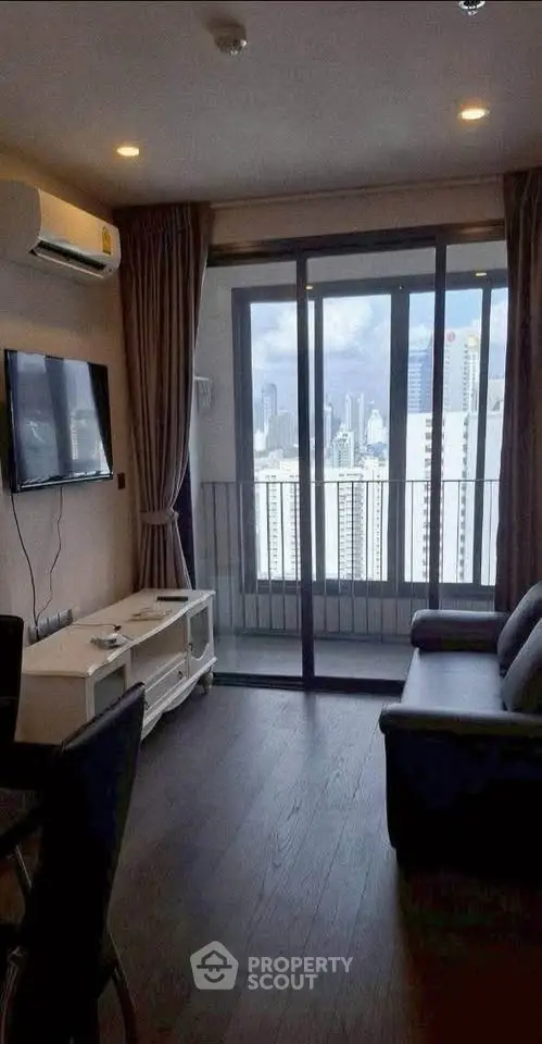 Modern living room with city view, featuring sleek furniture and large windows for natural light.