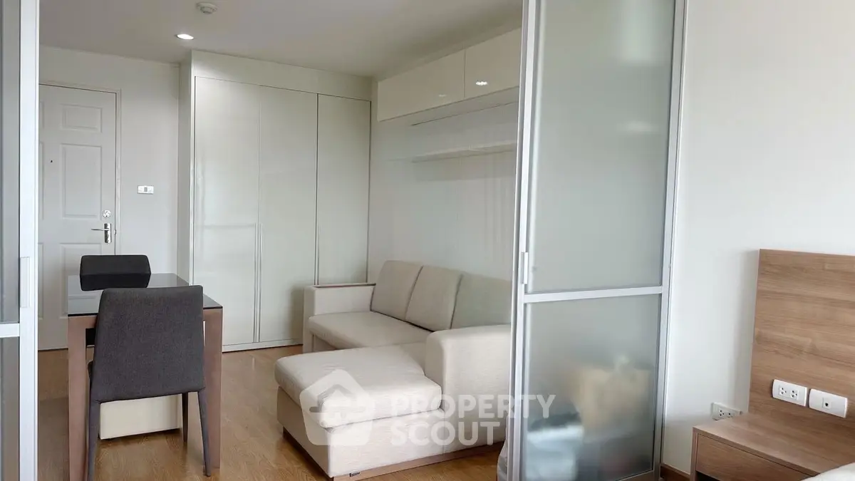 Modern living room with sleek furniture and sliding glass door in a cozy apartment.