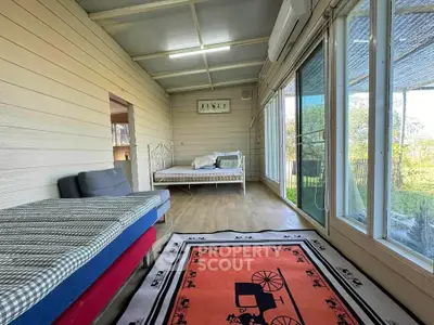 Charming sunlit room with large windows and cozy seating, perfect for relaxation and enjoying garden views.