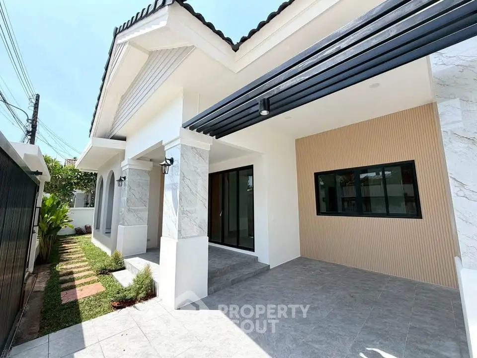 Modern single-story house with elegant exterior and spacious driveway, featuring stylish columns and lush landscaping.