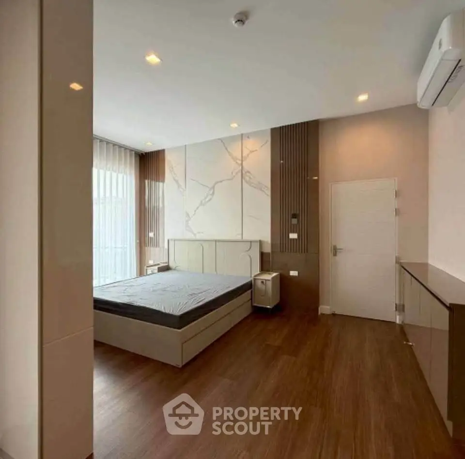 Modern bedroom with sleek design, wooden flooring, and large windows for natural light.