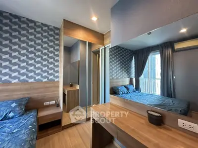 Modern bedroom with stylish geometric wallpaper and wooden furnishings, featuring a large mirror and natural light.