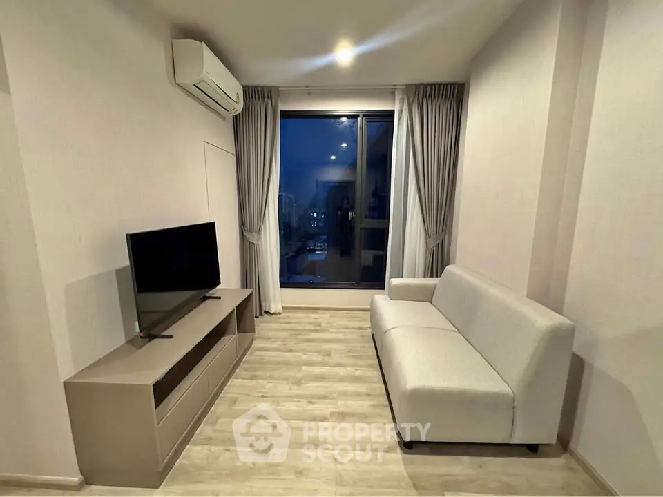 Modern living room with sleek furniture and large window offering city view