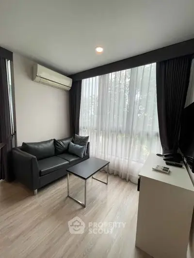 Modern living room with sleek black sofa and large window for natural light.