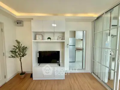 Modern living room with sleek white furniture and wooden flooring, featuring a TV and decorative plant.