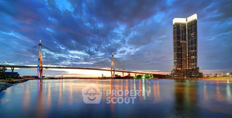 Stunning riverside view with modern bridge and high-rise building at sunset.