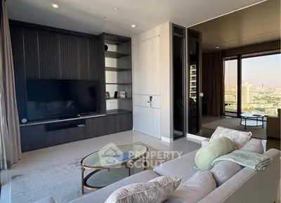 Modern living room with large TV and city view from balcony.