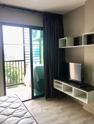 Modern bedroom with balcony access and wall-mounted TV in a stylish apartment.