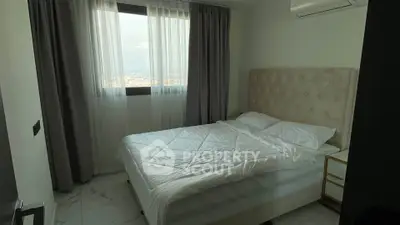 Cozy bedroom with plush headboard and city view from window.