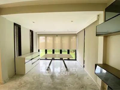 Spacious modern living room with marble flooring and large windows overlooking a garden.