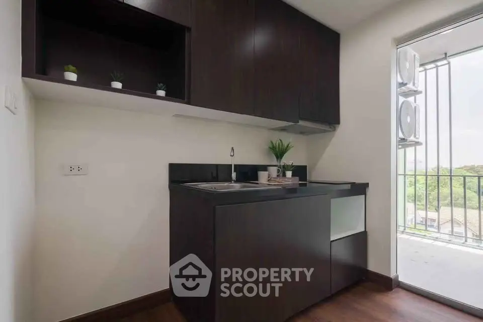 Modern compact kitchen with dark cabinetry and balcony view