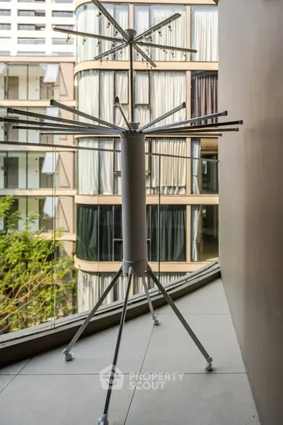 Modern apartment balcony with a view of contemporary architecture and a drying rack.