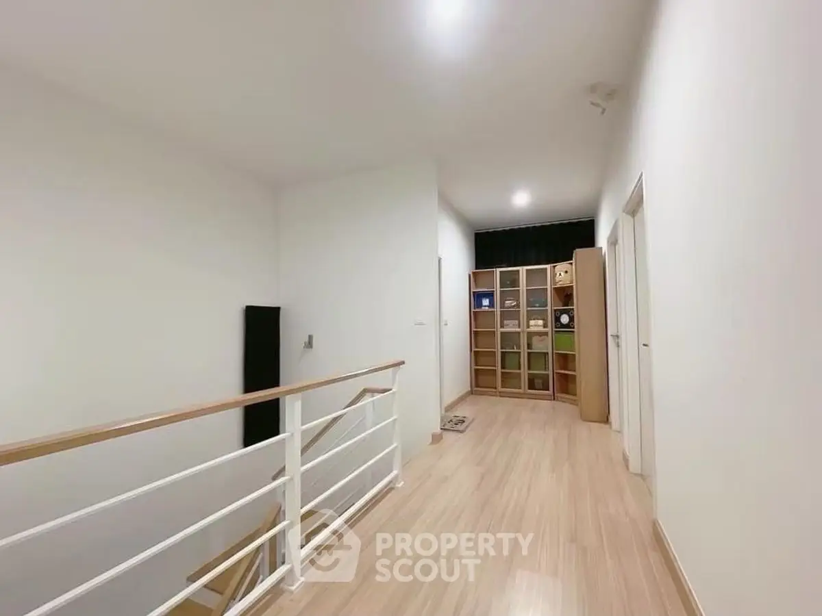 Spacious hallway with wooden flooring and modern railing in a stylish home.