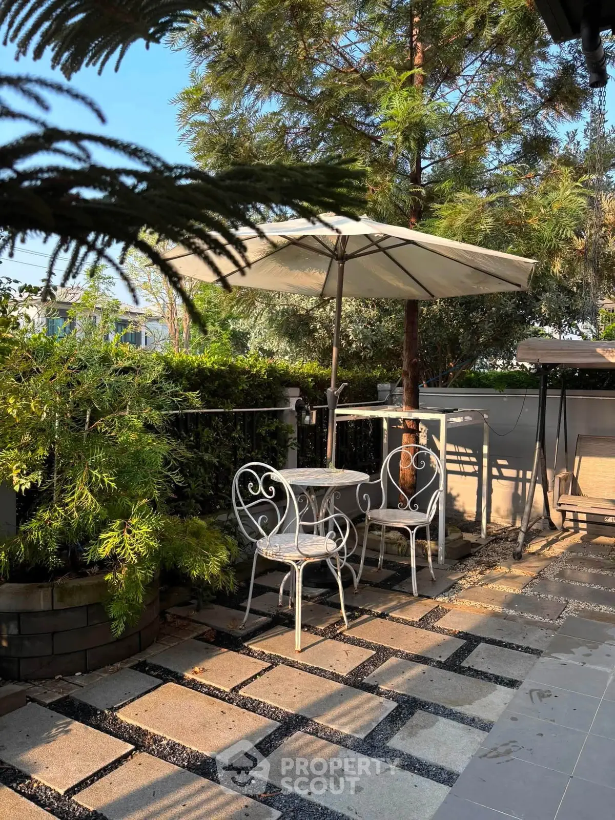 Charming garden patio with elegant seating and lush greenery, perfect for outdoor relaxation.